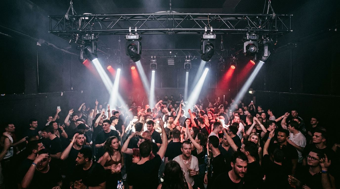 Crowd under haze and beam lights at an indoor gig